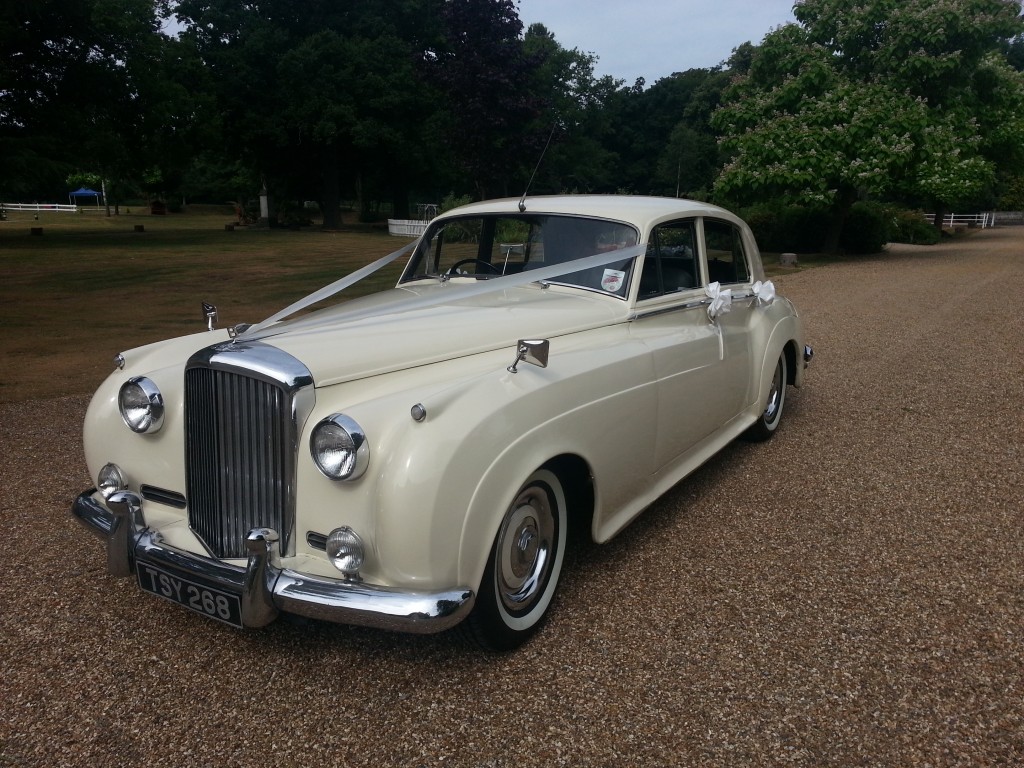 A classic white Bentley S1 available for rent, pictured outdoors.